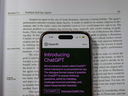 A smartphone on top of a book on problem-solving agents, the phone displays OpenAI's ChatGPT. 